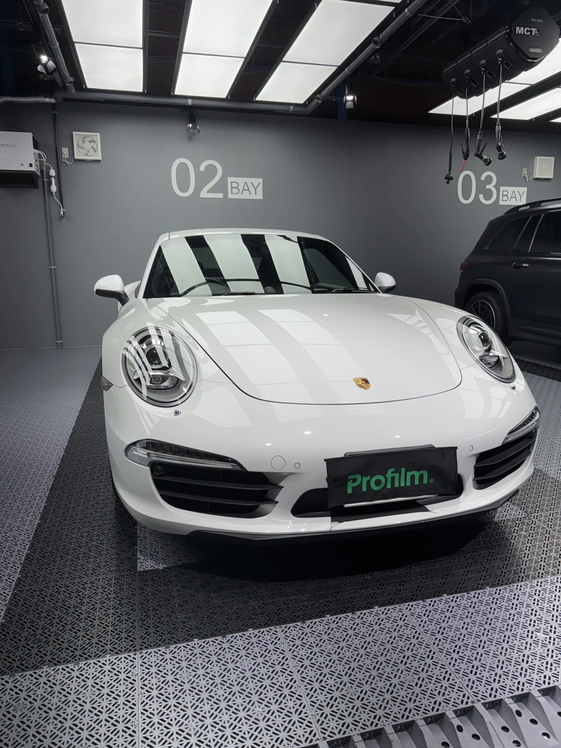 屋外で斜め前から撮影した白いポルシェ911のフロントボディ
